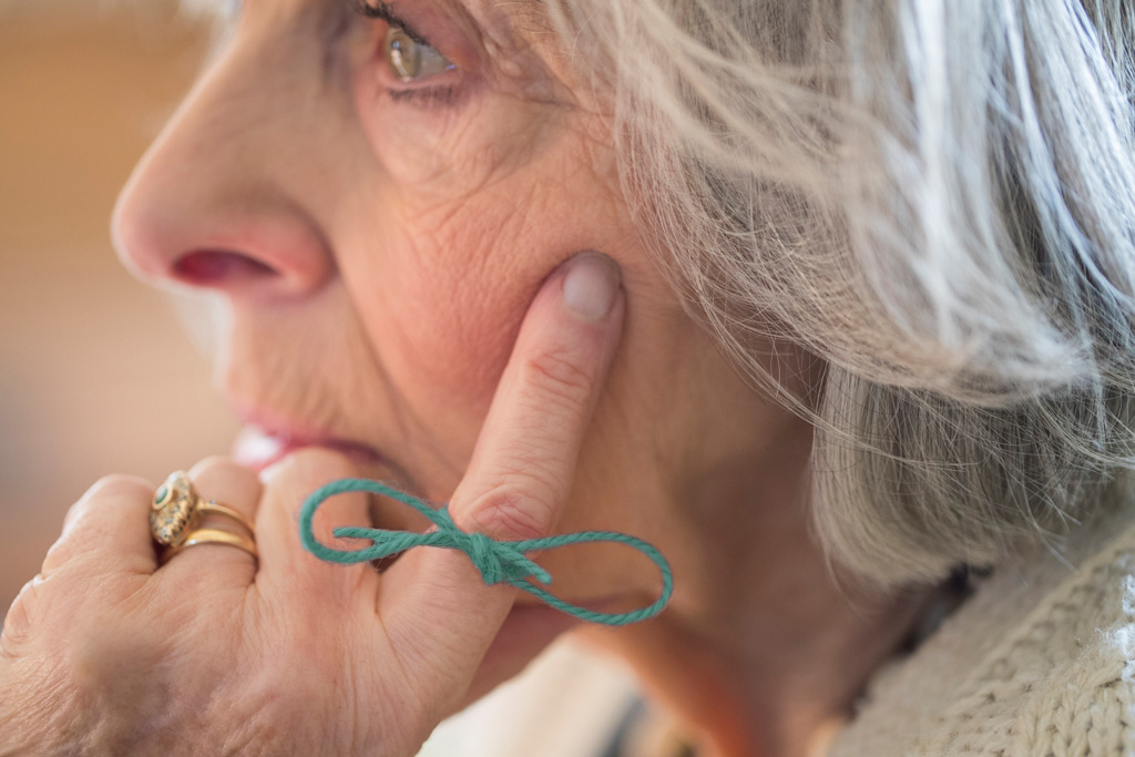 Bayerische Demenzwoche – Ältere Dame mit Schleife am Zeigefinger